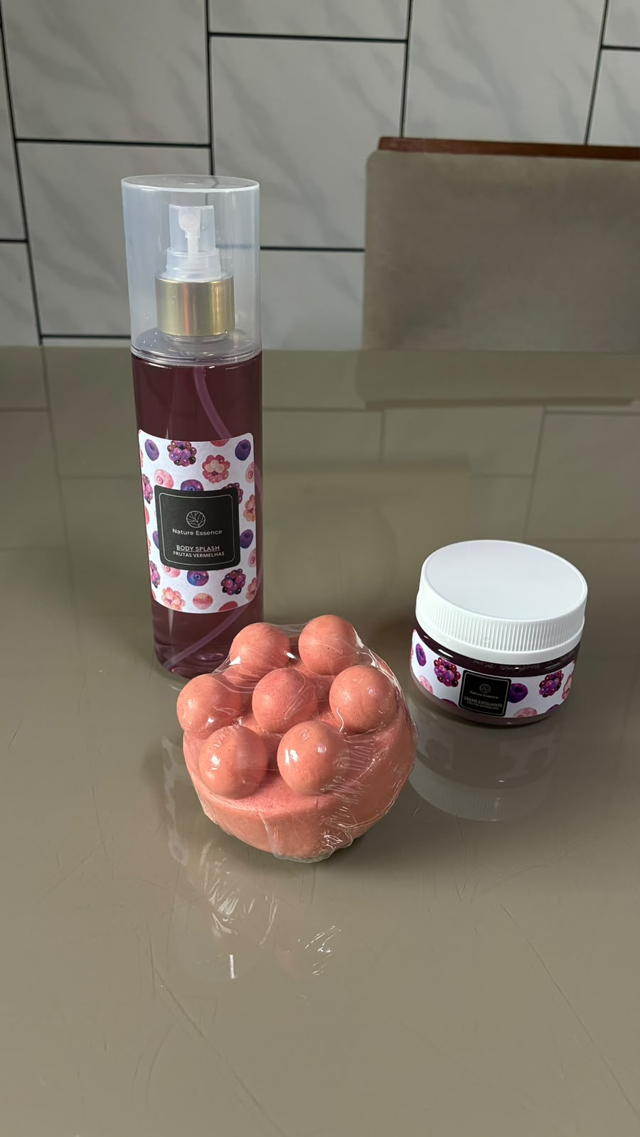 Kit Nature Essence com body splash Frutas Vermelhas, bomba de banho e creme esfoliante sobre bancada