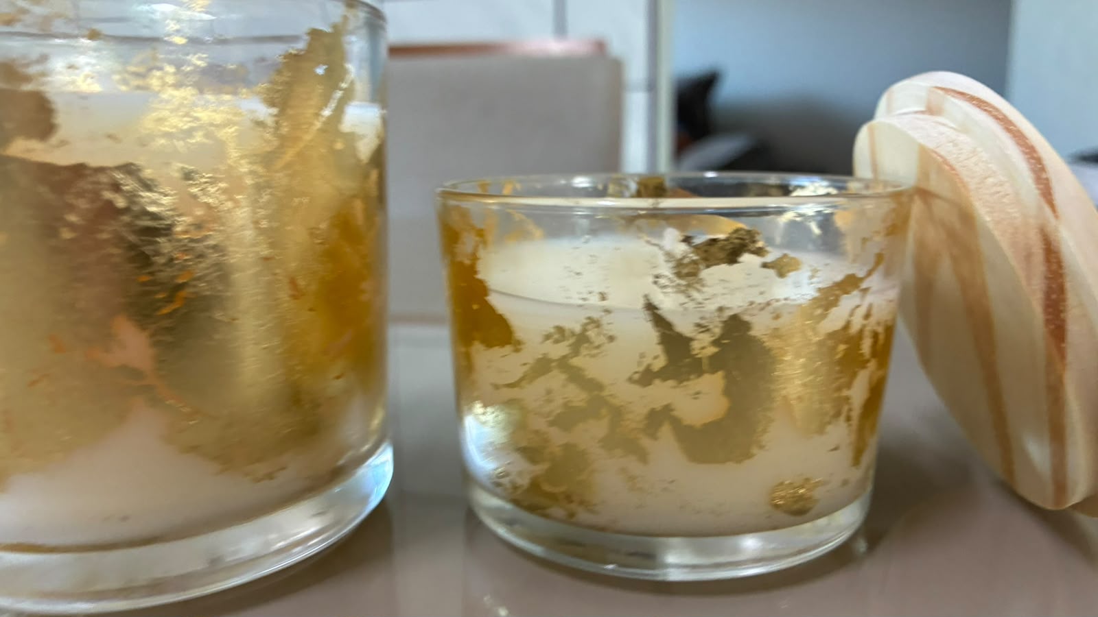 Par de velas em vidro decorado com folha de ouro, uma delas acesa